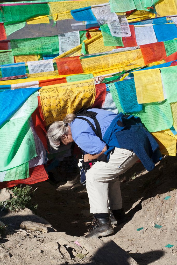 35-Marjolijn crawls under the prayer flags for a walk around the monastery.jpg - Marjolijn crawls under the prayer flags for a walk around the monastery